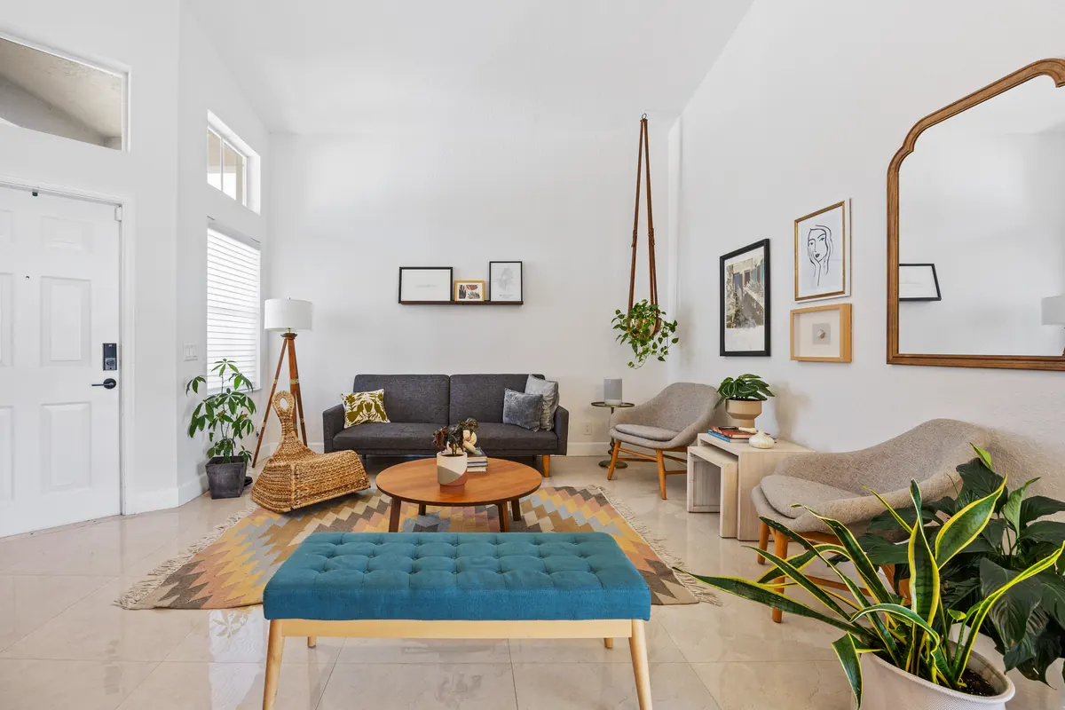 Bright living room with tall windows, a teal bench and hanging plants