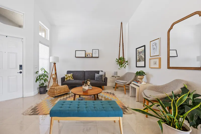 Bright living room with tall windows, a teal bench and hanging plants