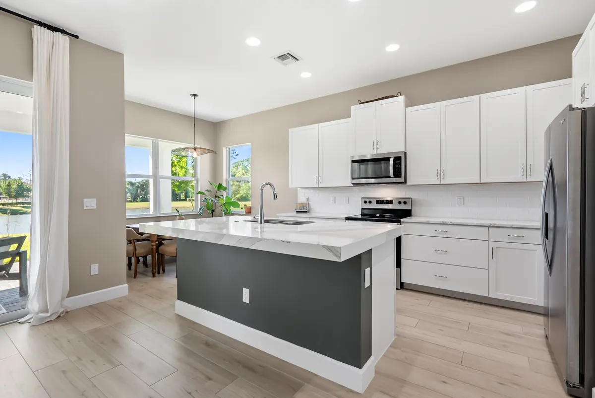 White kitchen with a dark island, stainless steel appliances and glass patio doors