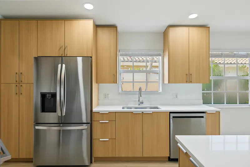Kitchen with natural wood cabinetry, stainless steel appliances and white counters