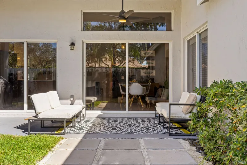Outdoor seating on a wood deck beside broad glass doors
