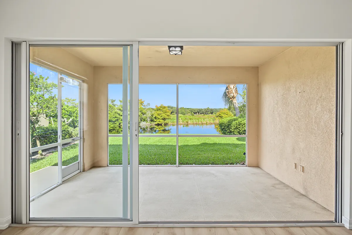 Screened covered patio overlooking a lawn and lake