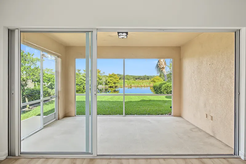 Screened covered patio overlooking a lawn and lake