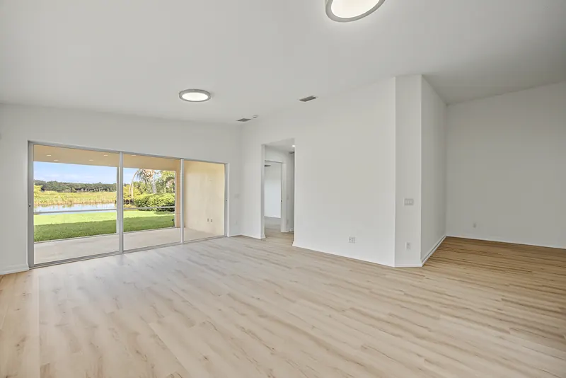 Unfurnished living room with wood-look flooring and sliding doors to a screened patio