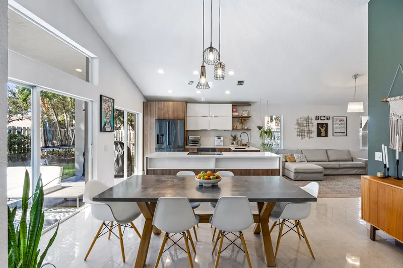 Dining area with a dark accent wall and an open view into the kitchen and living room